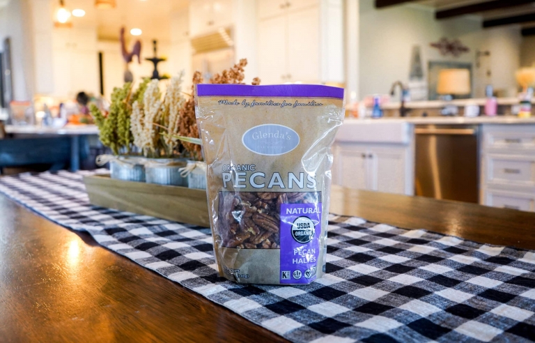 A bag of organic pecans sits on a kitchen table.