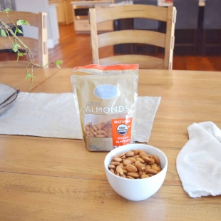 A kitchen table with a bowl of organic almonds.