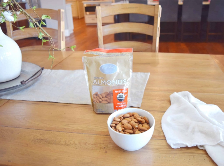 A kitchen table with a bowl of organic almonds.