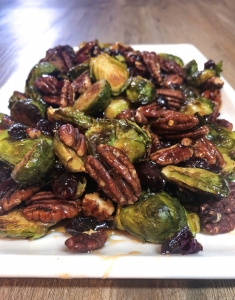 A platter of Roasted Brussel Sprouts with pecans and a spicy maple drizzle.