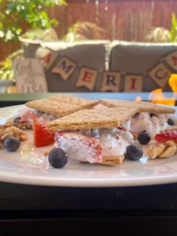 3 decadent smores on a plate, featuring blueberries, strawberries and walnuts.