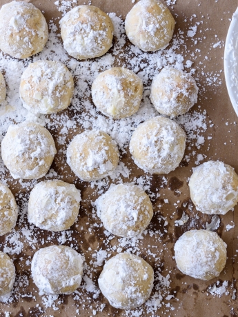 Almond cookies that are shaped like ball, rolled in powered sugar and cooling.