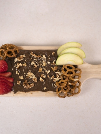 A butter board made with cocoa almond butter, organic walnuts, strawberries, and green apples.