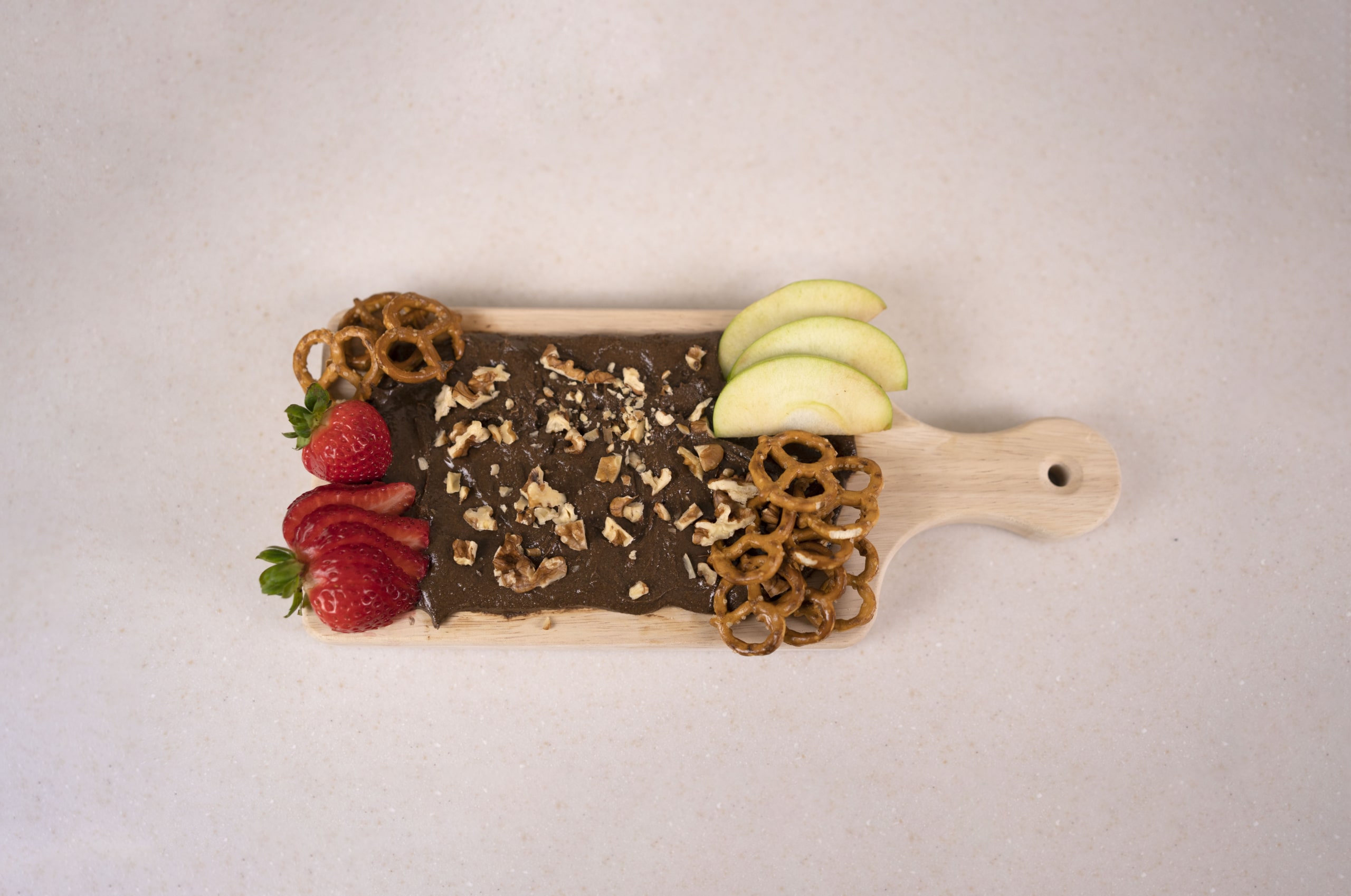 A butter board made with cocoa almond butter, organic walnuts, strawberries, and green apples.