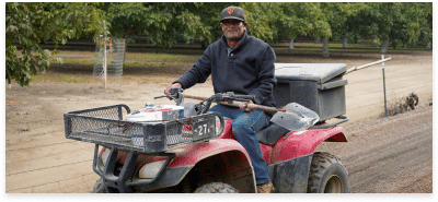 a man on a four wheeler holding a shovel with a plastic box on the back